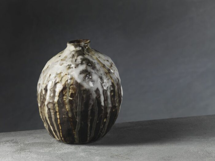 Coil built vessel with dribbles of glaze over it, slips and ash glazes
