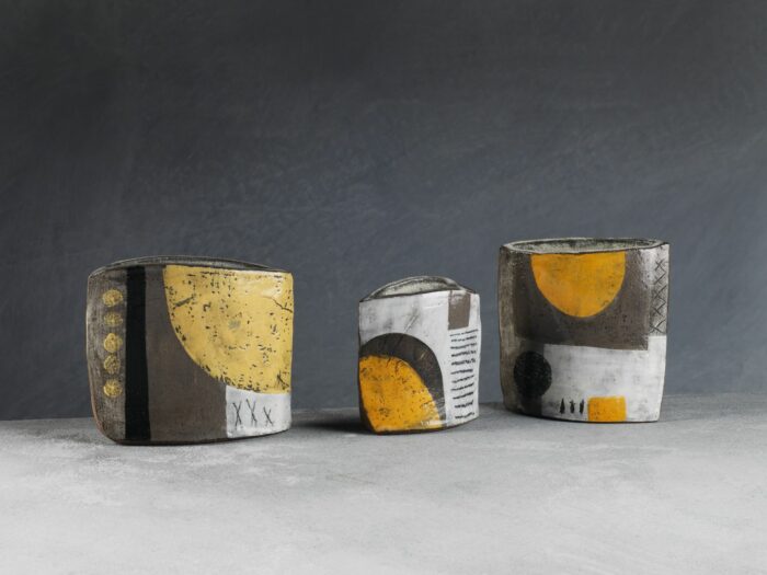 Three hand built pots each decorated with shapes and colour